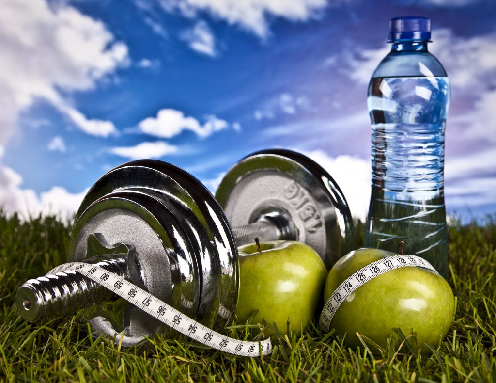 Apples next to a dumbell with a water bottle in the background